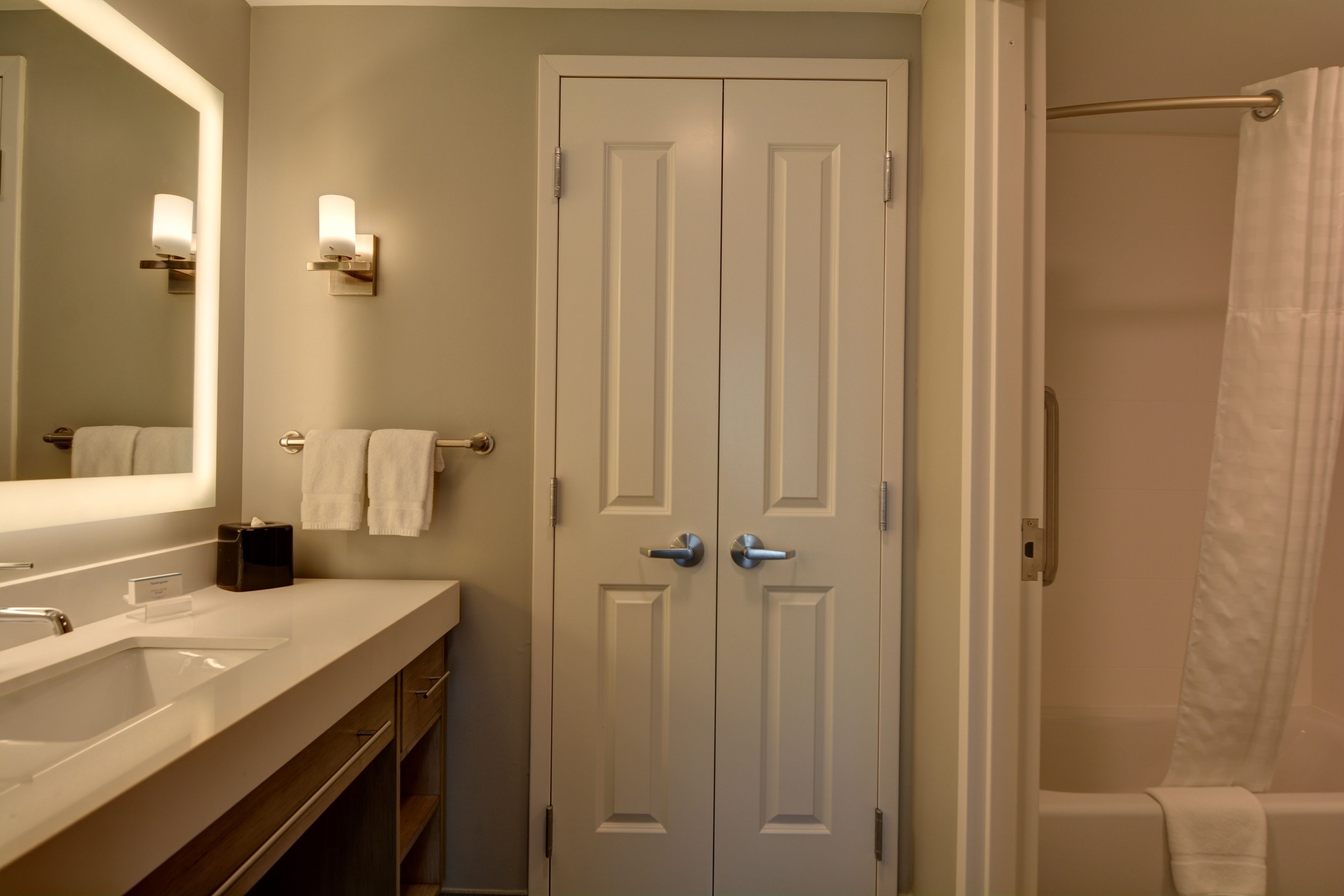 A bathroom with a white sink, mirror, and double doors.