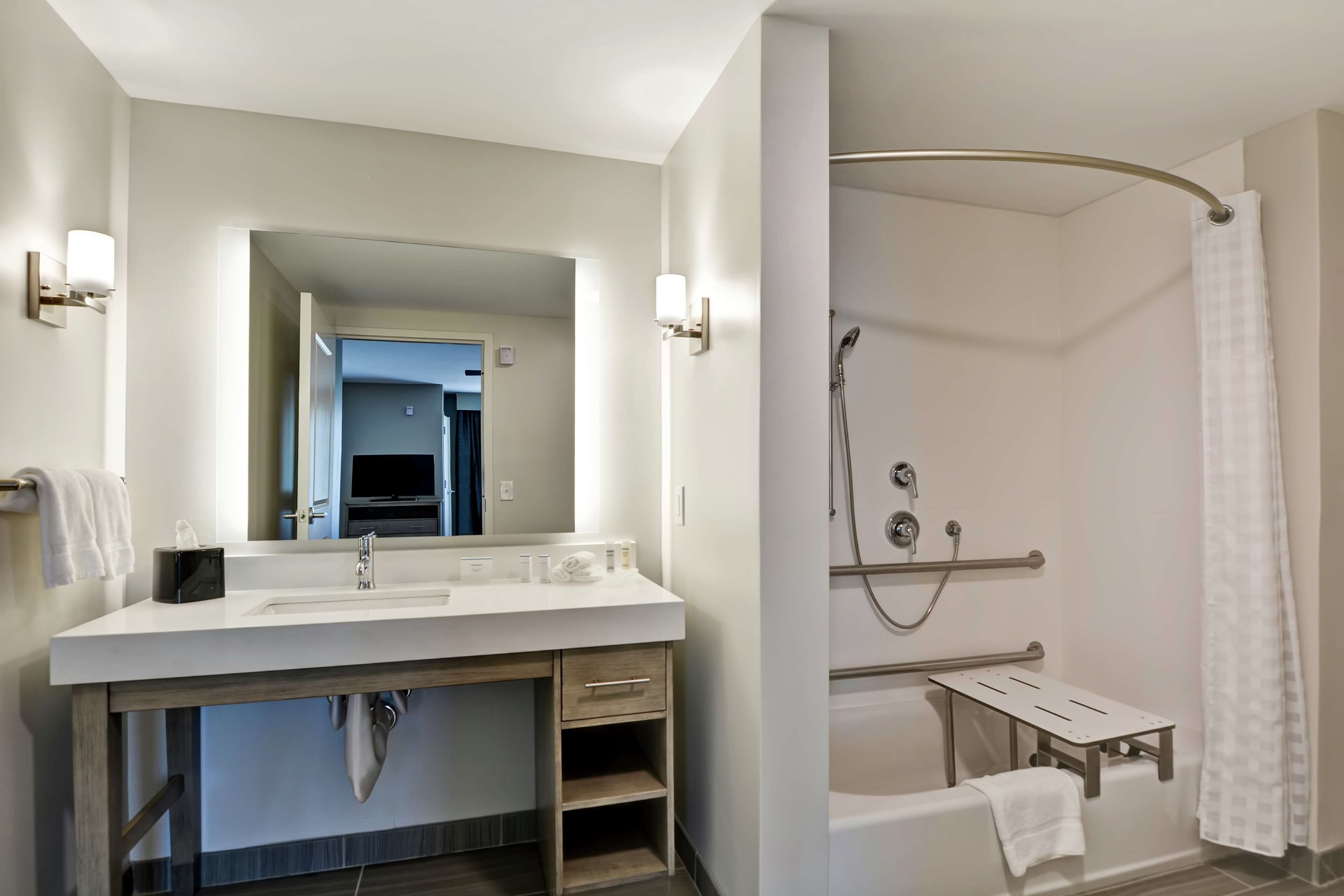 A modern bathroom with a white sink, mirror, and shower.