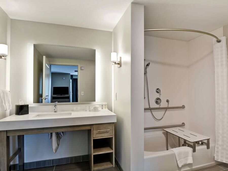 A modern bathroom with a white sink, mirror, and shower.