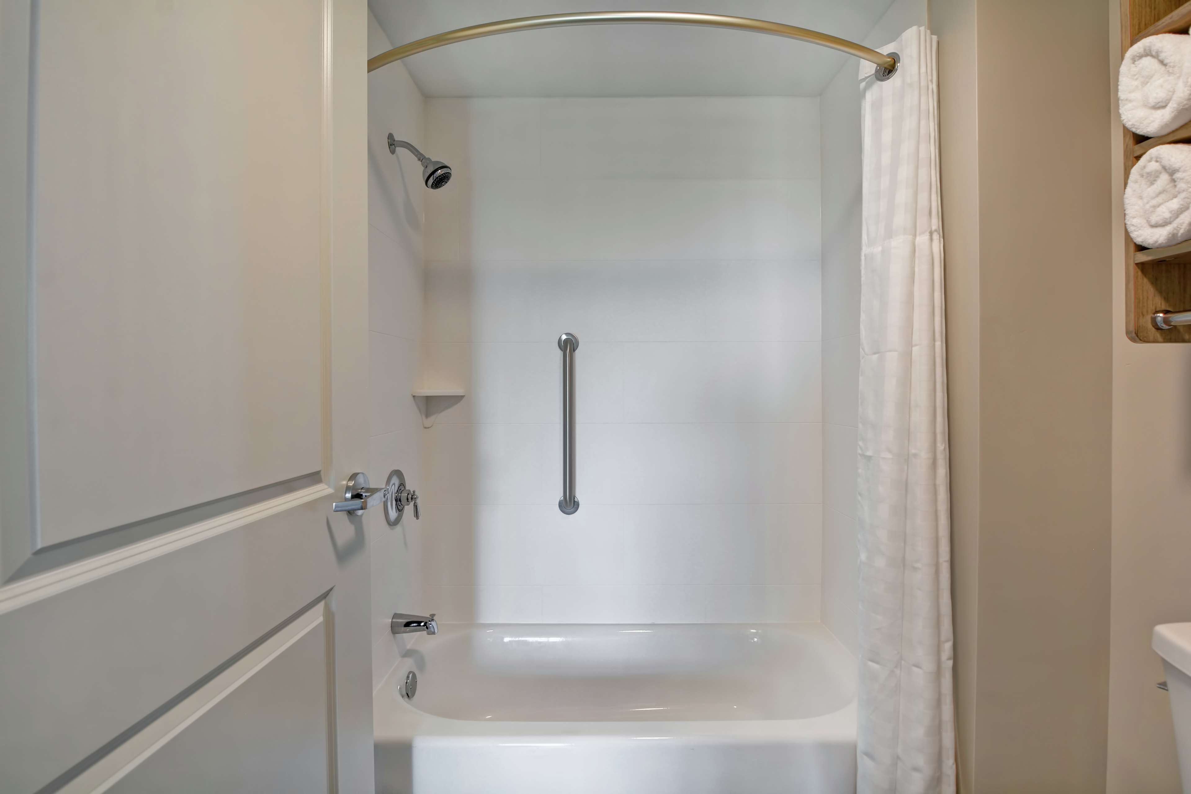 A bathroom with a bathtub, a shower with a glass door, and a towel rack with towels.