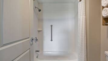 A bathroom with a bathtub, a shower with a glass door, and a towel rack with towels.