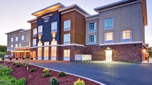 A modern hotel with a brick facade, multiple windows, and a well-lit entrance. - Homewood Suites by Hilton Hadley Amherst (Hadley)