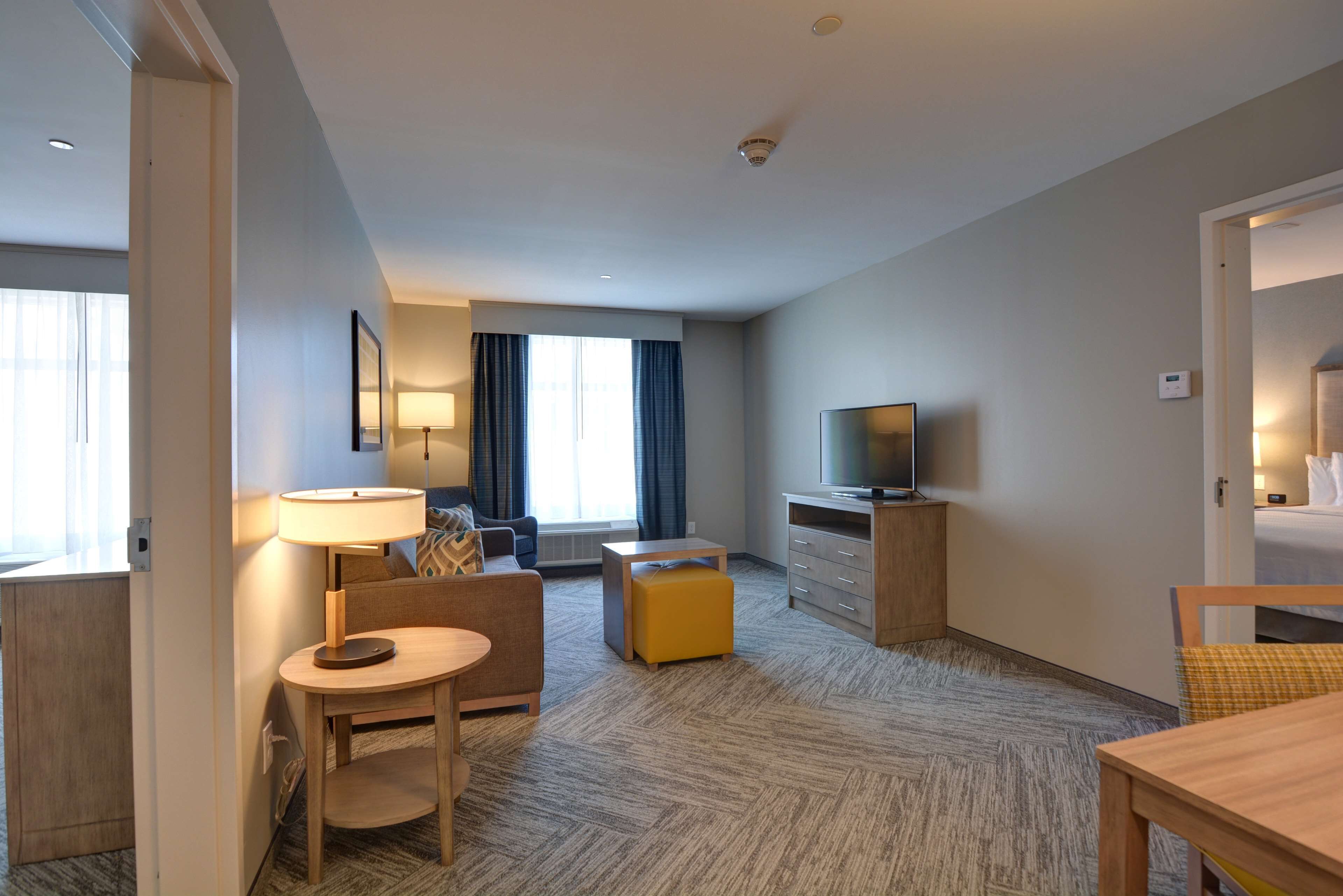 Habitación de hotel con sofá, una mesita, televisor y lámpara.