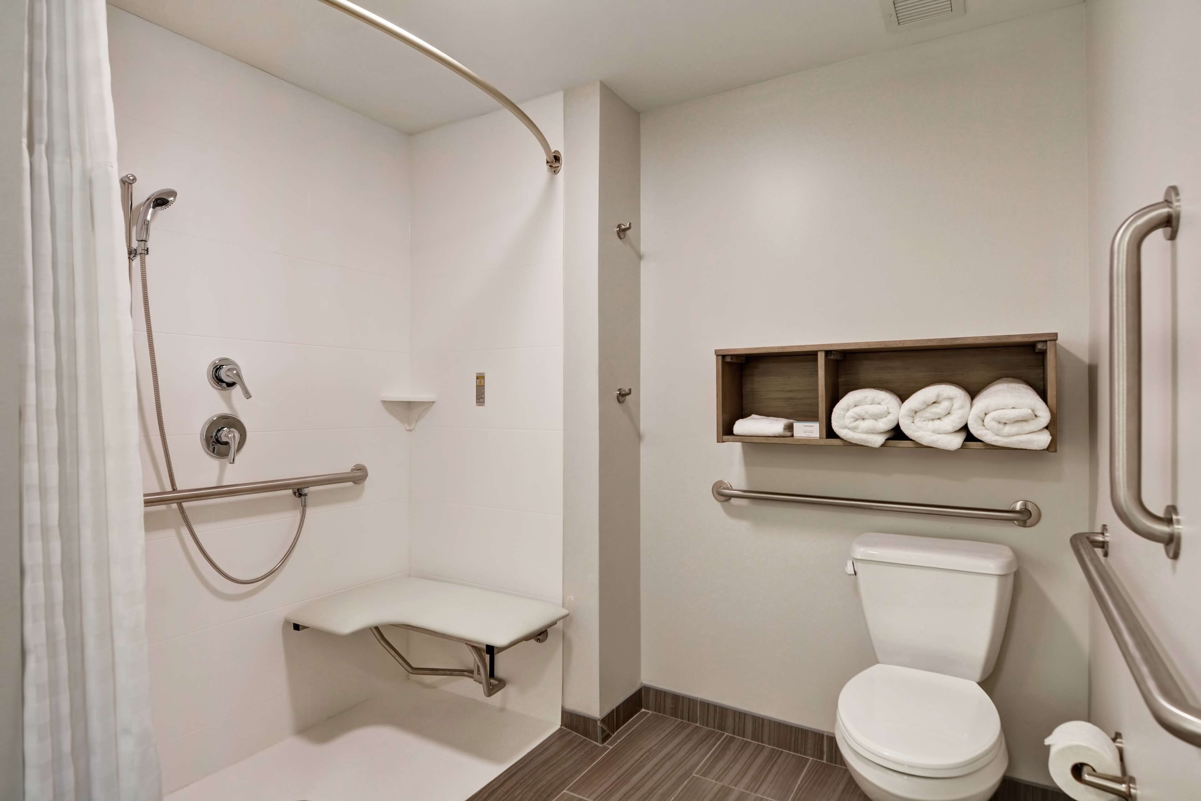 Un baño moderno con ducha, inodoro y un estante con toallas.