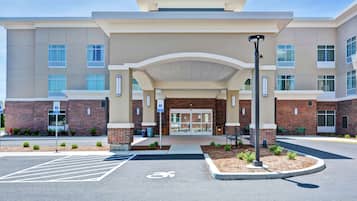 A modern building with a covered entrance, brick facade, and a parking area with a bicycle symbol.