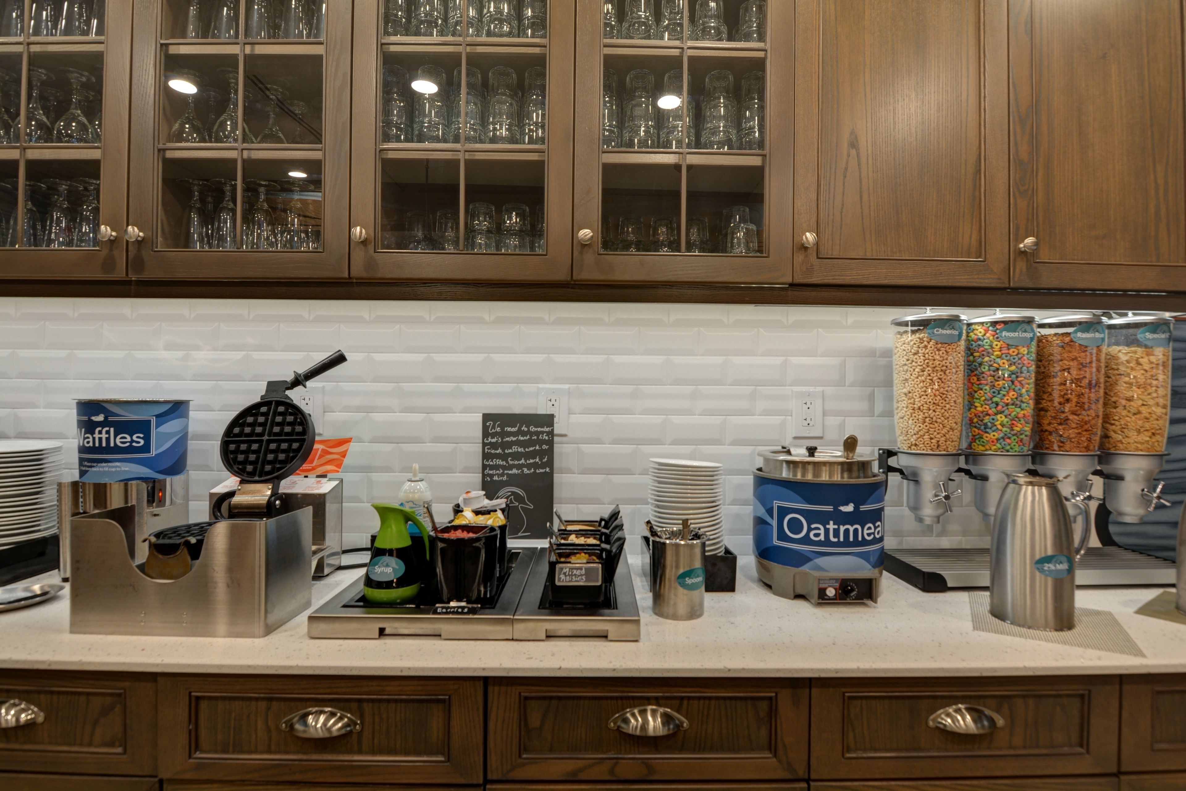 A breakfast bar with waffle maker, coffee station, and cereal dispensers.