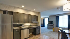 A modern kitchen with stainless steel appliances, a microwave, and a dishwasher. There is a dining area with a table and chairs. - Homewood Suites by Hilton Hadley Amherst (Hadley)