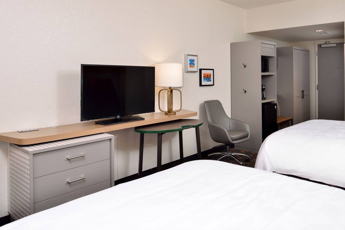 Een hotelkamer met een bed, een bureau met een televisie, een stoel, een klein tafeltje en een kledingkast.