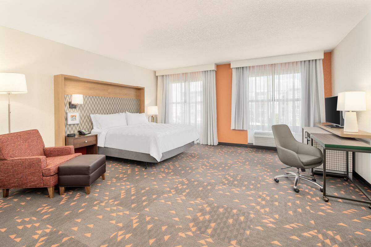 A hotel room with a bed, a desk, a chair, and a sofa.