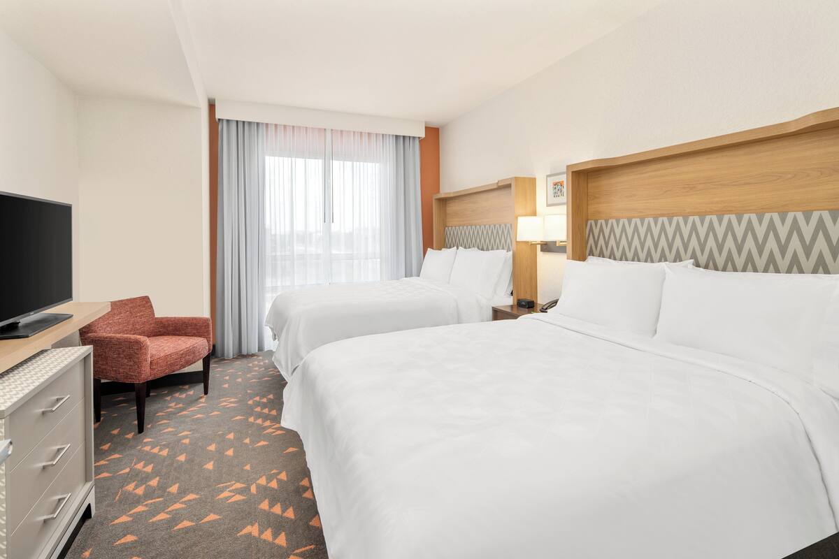 Een hotelkamer met twee bedden, een televisie, een bureau en een stoel.