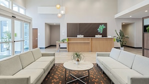 A modern hotel lobby with two sofas, a reception desk, and a large window.
