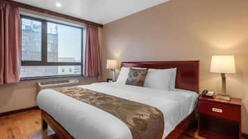 Una habitación de hotel con una cama grande, dos lámparas de noche, una mesita de noche con un teléfono y una ventana con cortinas.