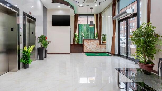 Un moderno vestíbulo de hotel con ascensores, una mesa de recepción y plantas en macetas.