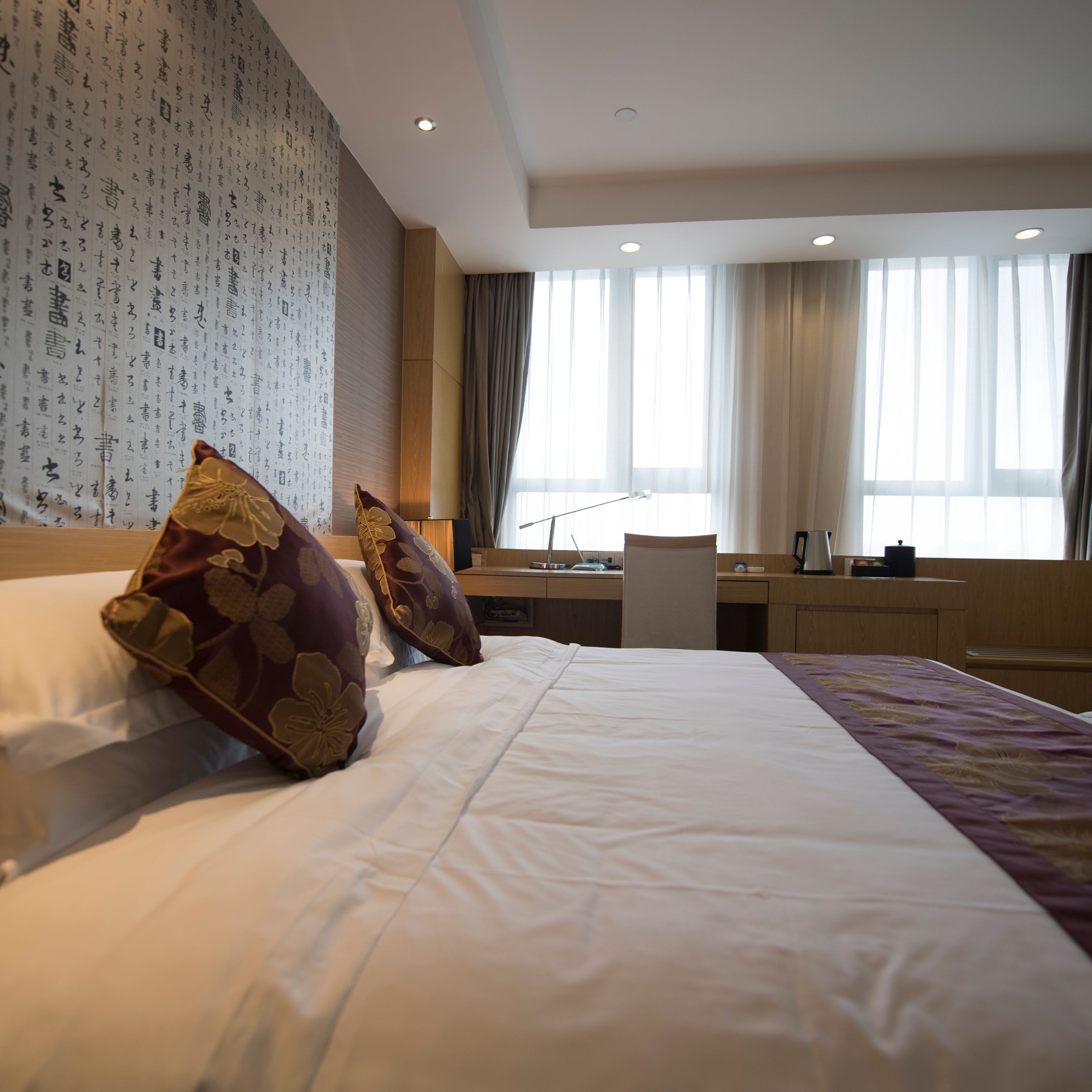 Habitación de hotel con una cama grande, un escritorio y vistas a la ciudad a través de la ventana.