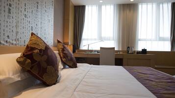 Habitación de hotel con una cama grande, un escritorio y vistas a la ciudad a través de la ventana.