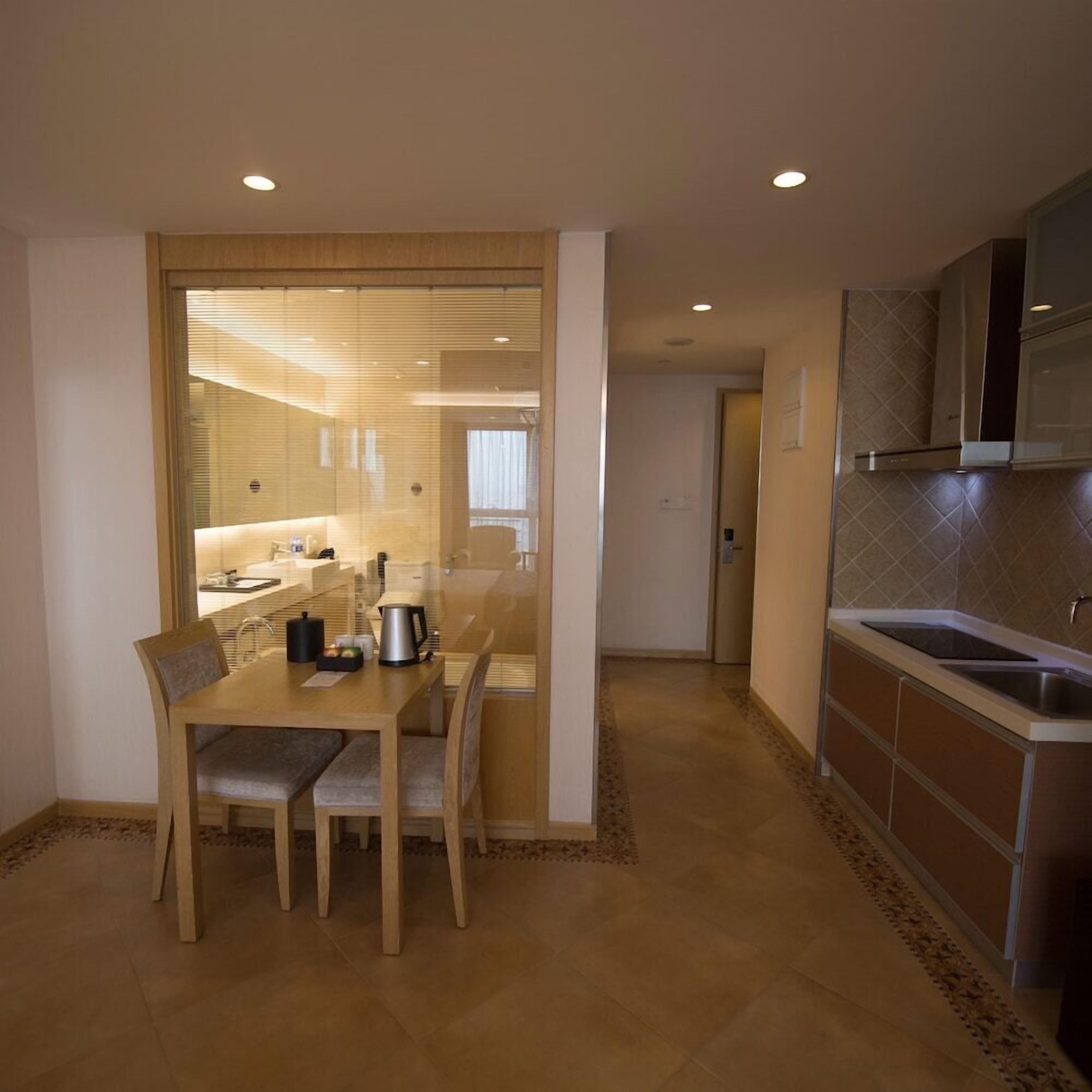 A modern kitchen with a dining area, featuring a wooden table and chairs, a built-in oven, and a sink.
