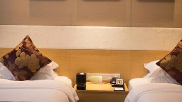 Habitación de hotel con dos camas, una mesita de noche con teléfono y lámpara, y tres cuadros enmarcados en la pared.