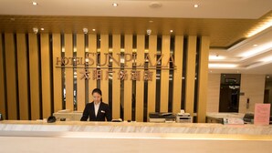 Een receptiebalie van een hotel met een houten paneel waarop de naam van het hotel staat.
