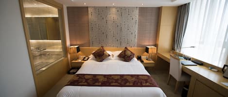 Una habitación de hotel con una cama grande, un escritorio y una ventana con cortinas.