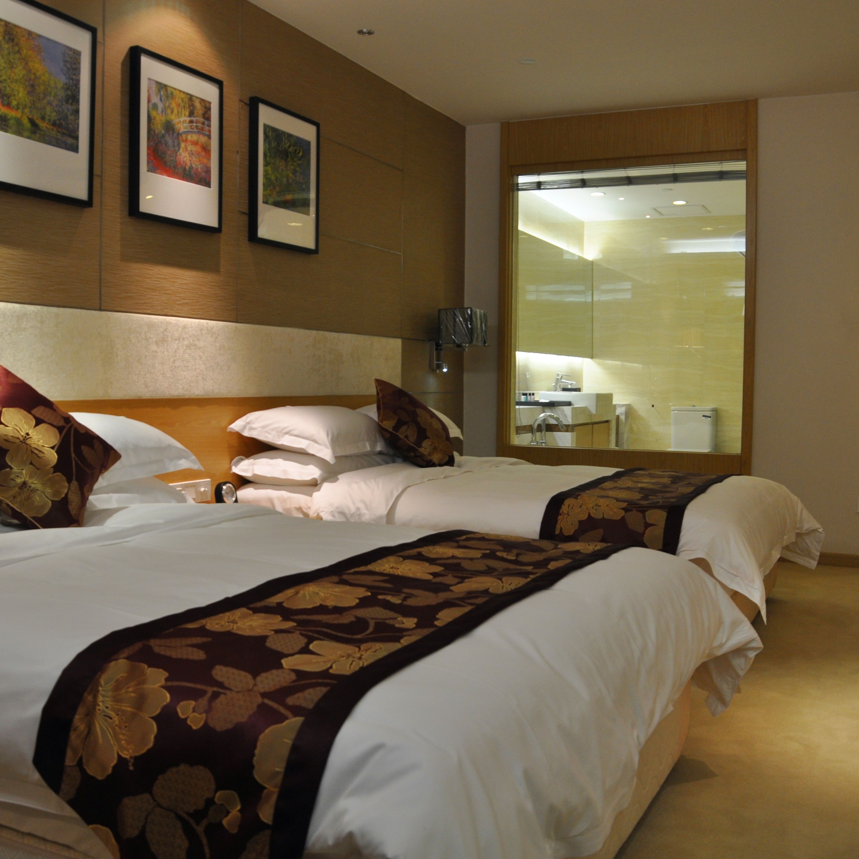 Ein Hotelzimmer mit zwei Betten, einem großen Spiegel und Bildern an der Wand.