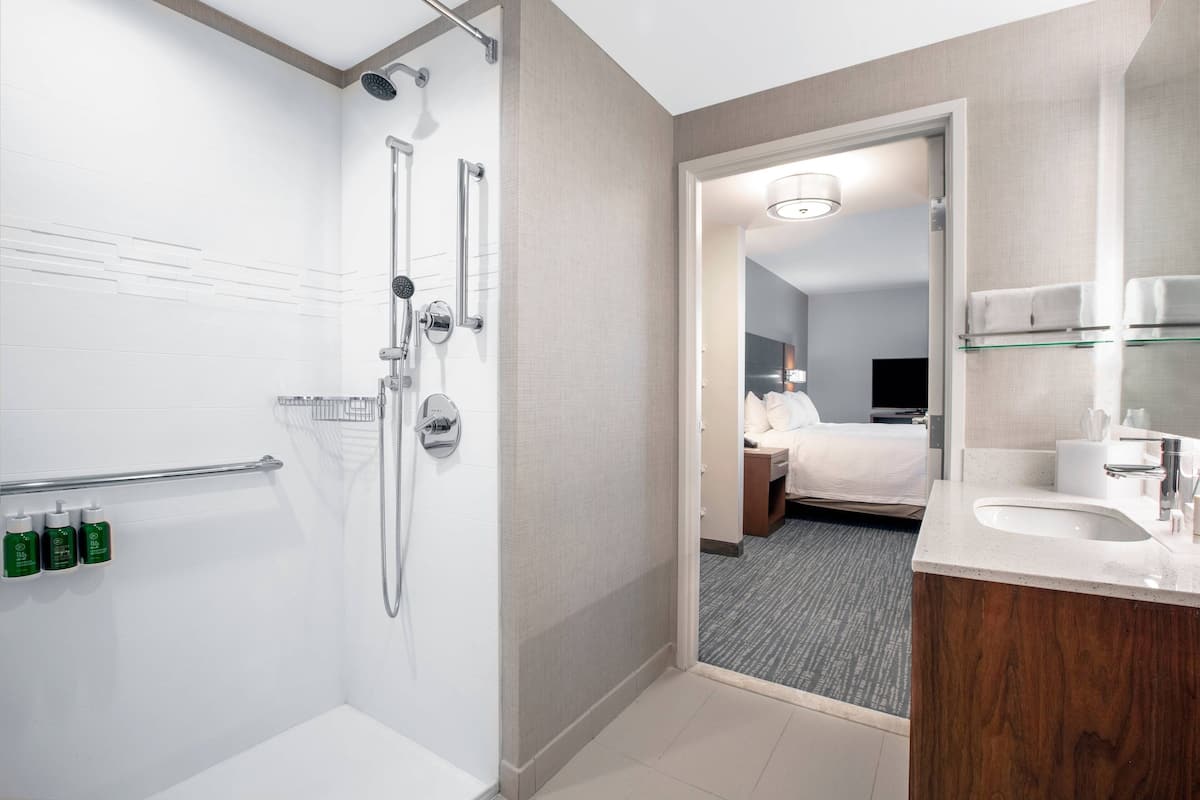 A modern hotel bathroom with a shower, toilet, and sink.