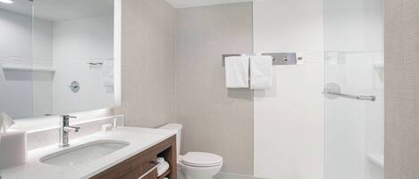Un baño moderno con un espejo grande, un lavabo, un inodoro y una zona de ducha.