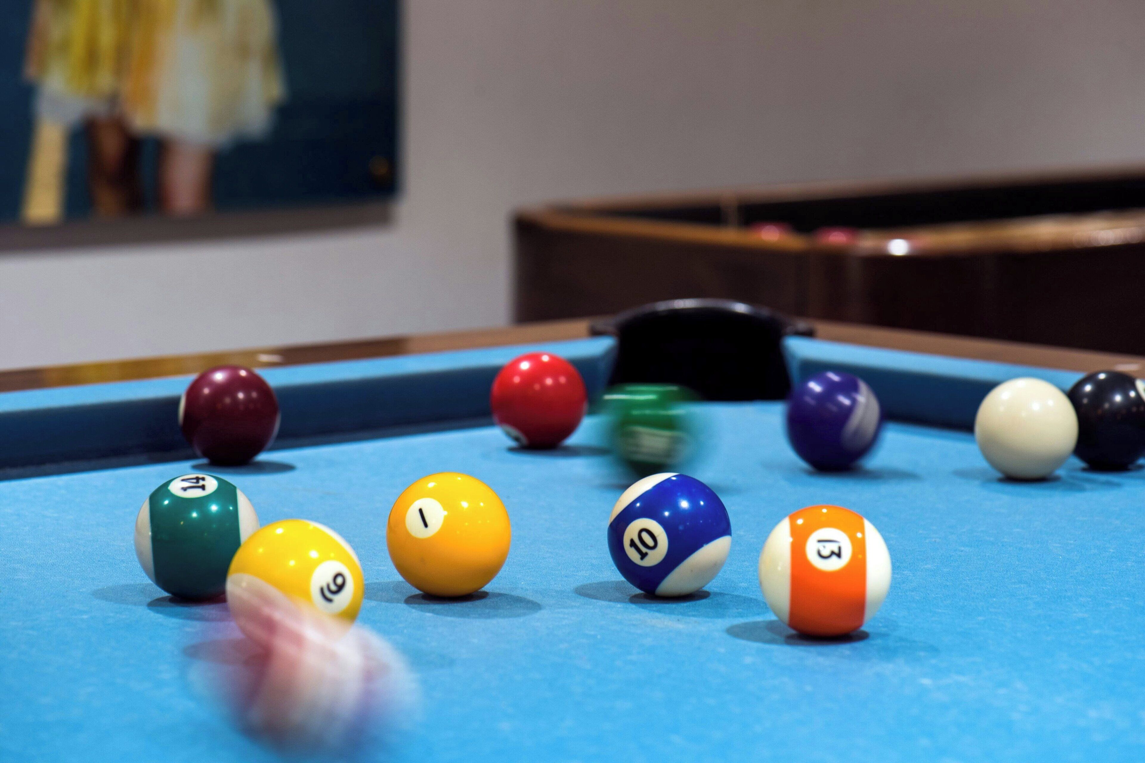 A pool table with numbered balls and a cue stick.