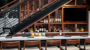 Un espace bar avec un escalier, des chaises en bois et une variété de bouteilles et de verres.