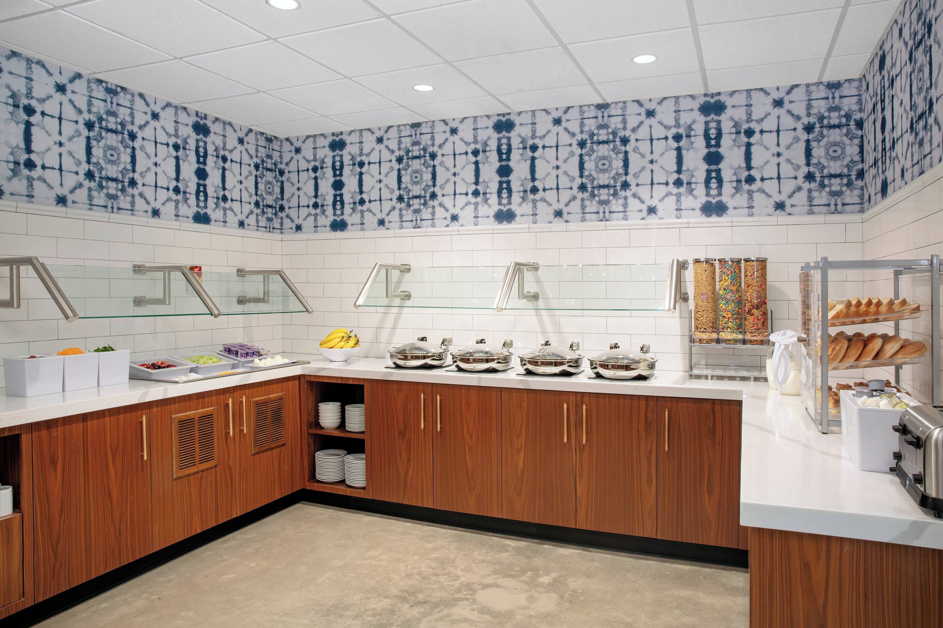Una cucina moderna con piani di lavoro bianchi, mobili in legno e piastrelle blu e bianche decorate alle pareti.
