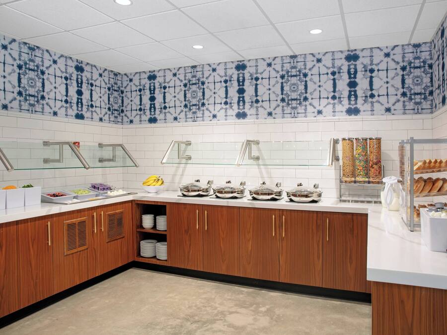 Una cucina moderna con piani di lavoro bianchi, mobili in legno e piastrelle blu e bianche decorate alle pareti.