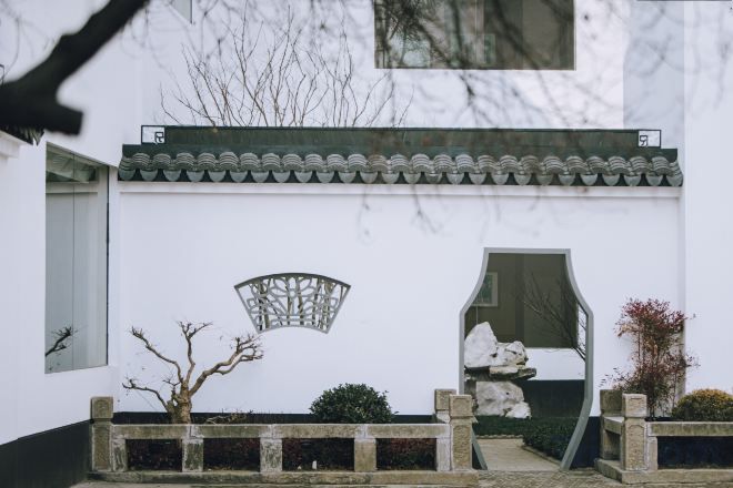 A traditional building with a white exterior, a tiled roof, and a small entrance with a gate.