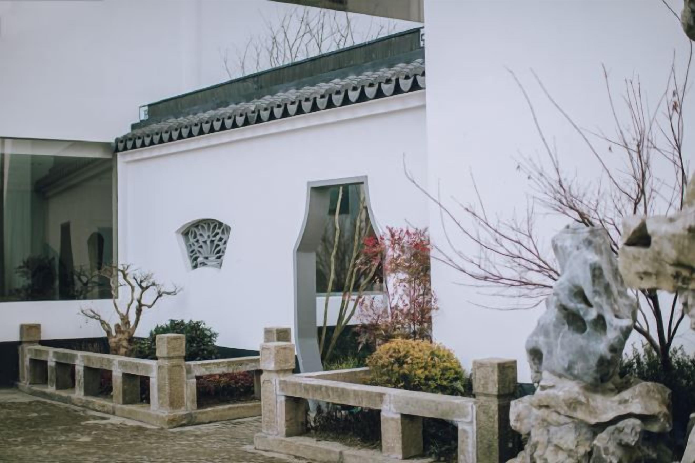 A traditional building with a white exterior, large windows, and a stone pathway leading to the entrance.