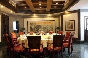 Comedor con una mesa redonda dispuesta para seis personas, rodeada de sillas tapizadas en rojo.