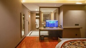 A hotel room with a bed, a desk with a computer, a wardrobe, and a mirror. - Songling Hotel (Suzhou)