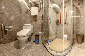 A modern bathroom with a toilet, a glass-enclosed shower, and marble walls. - Songling Hotel (Suzhou)