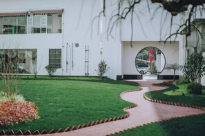 A pathway leading to a building with a circular driveway, surrounded by a well-maintained lawn and a few shrubs. - Songling Hotel (Suzhou)