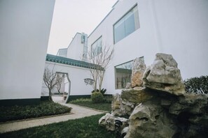 Un edificio moderno con fachada blanca, un sendero de piedra y una formación rocosa al frente.