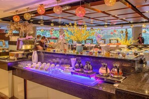 Una zona de bar con una barra alargada, distintos utensilios para coctelería y elementos decorativos como faroles colgantes y arreglos florales.