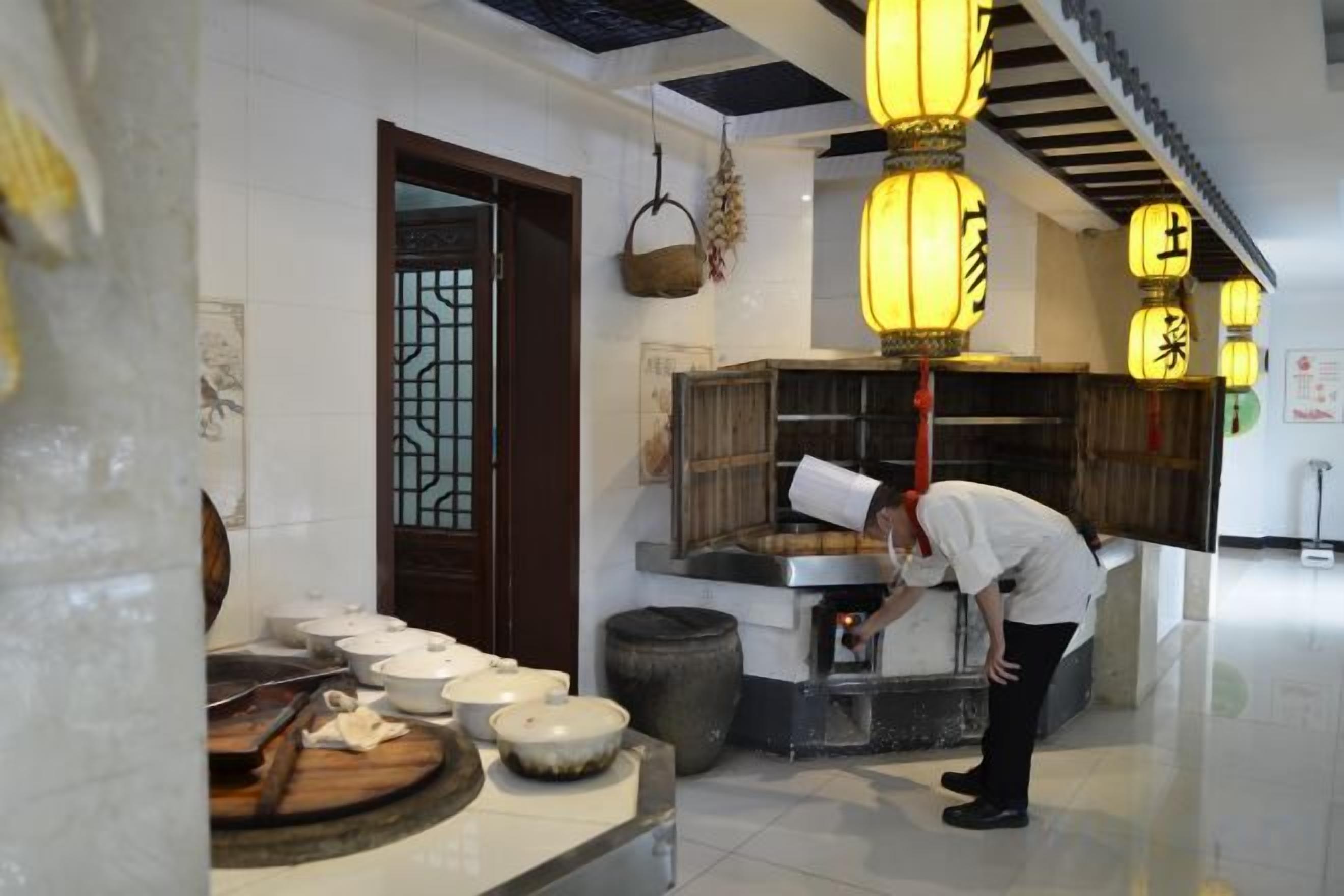 A kitchen area with a chef preparing food, a traditional door, and hanging lanterns.