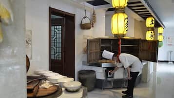 A kitchen area with a chef preparing food, a traditional door, and hanging lanterns.