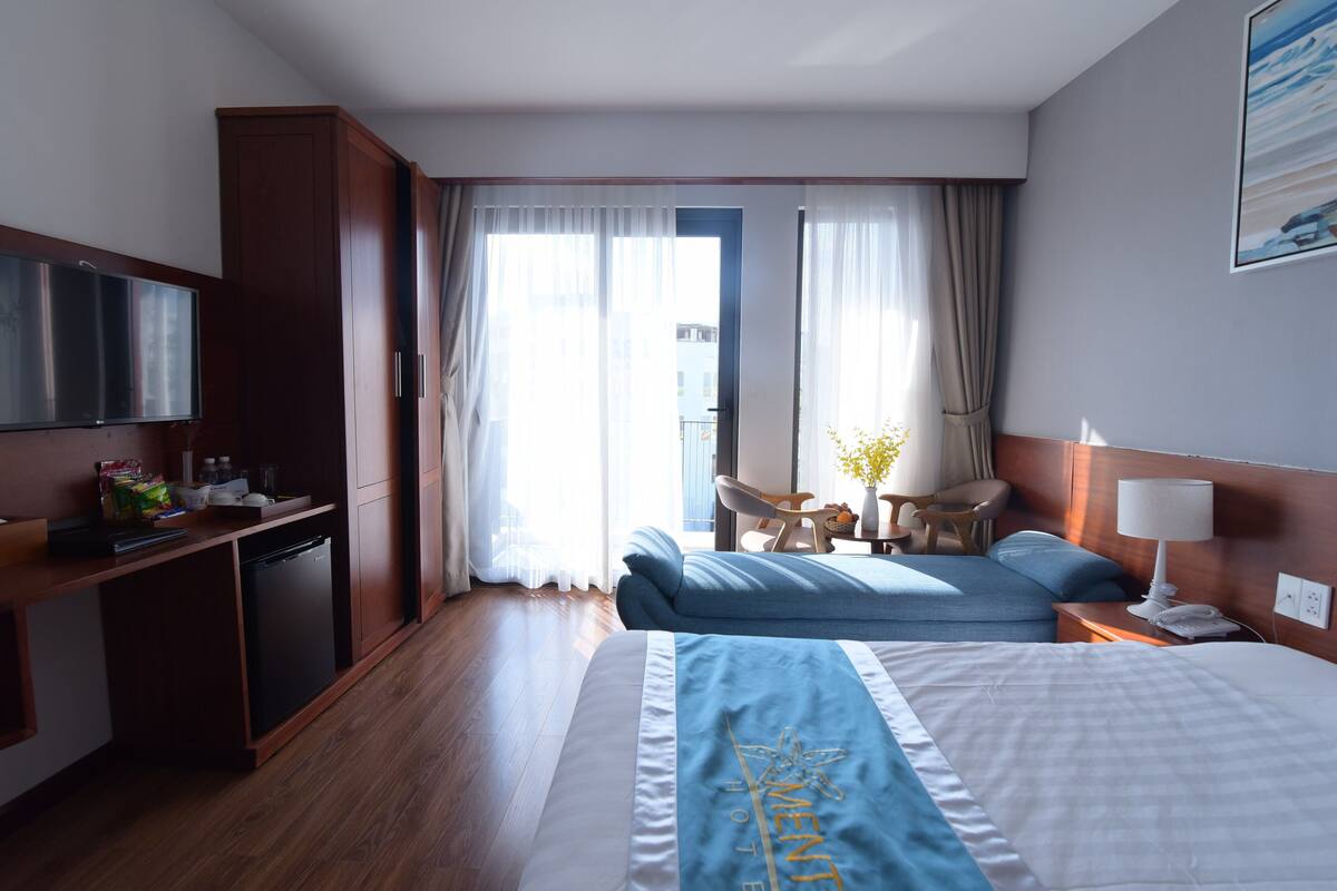 Ein Hotelzimmer mit Bett, Schreibtisch, Stuhl, kleinem Tisch und Fernseher.