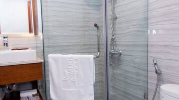 A modern bathroom with a glass-enclosed shower, a white toilet, and a wooden vanity.