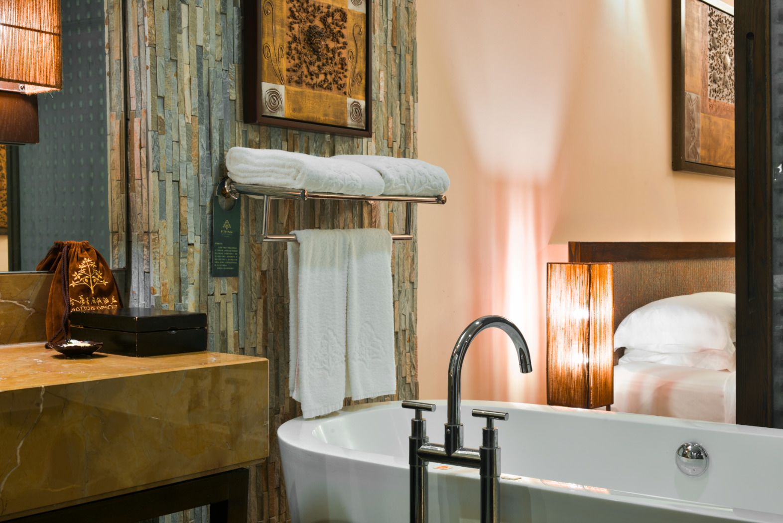 Un baño moderno con una bañera independiente, encimera de mármol y panel de pared de madera.