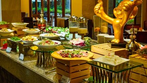 A buffet with various dishes, a golden elephant statue, and a view of the outdoors through large windows. - Pattra Resort Hotel (Guangzhou)