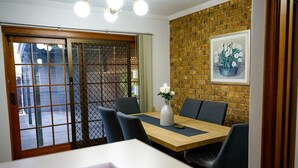 A dining area with a wooden table, grey chairs, and a vase with white flowers. - Adelaide Style Accommodation near City (North Adelaide)