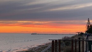 A coastal sunset view with a pier extending into the water. - Adelaide Style Accommodation near City (North Adelaide)