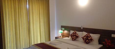 A hotel room with a large bed, a nightstand with a lamp, and a ceiling fan.