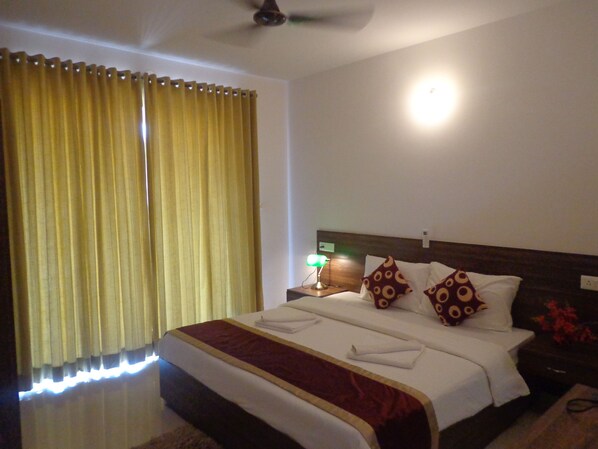 A hotel room with a large bed, a nightstand with a lamp, and a ceiling fan.