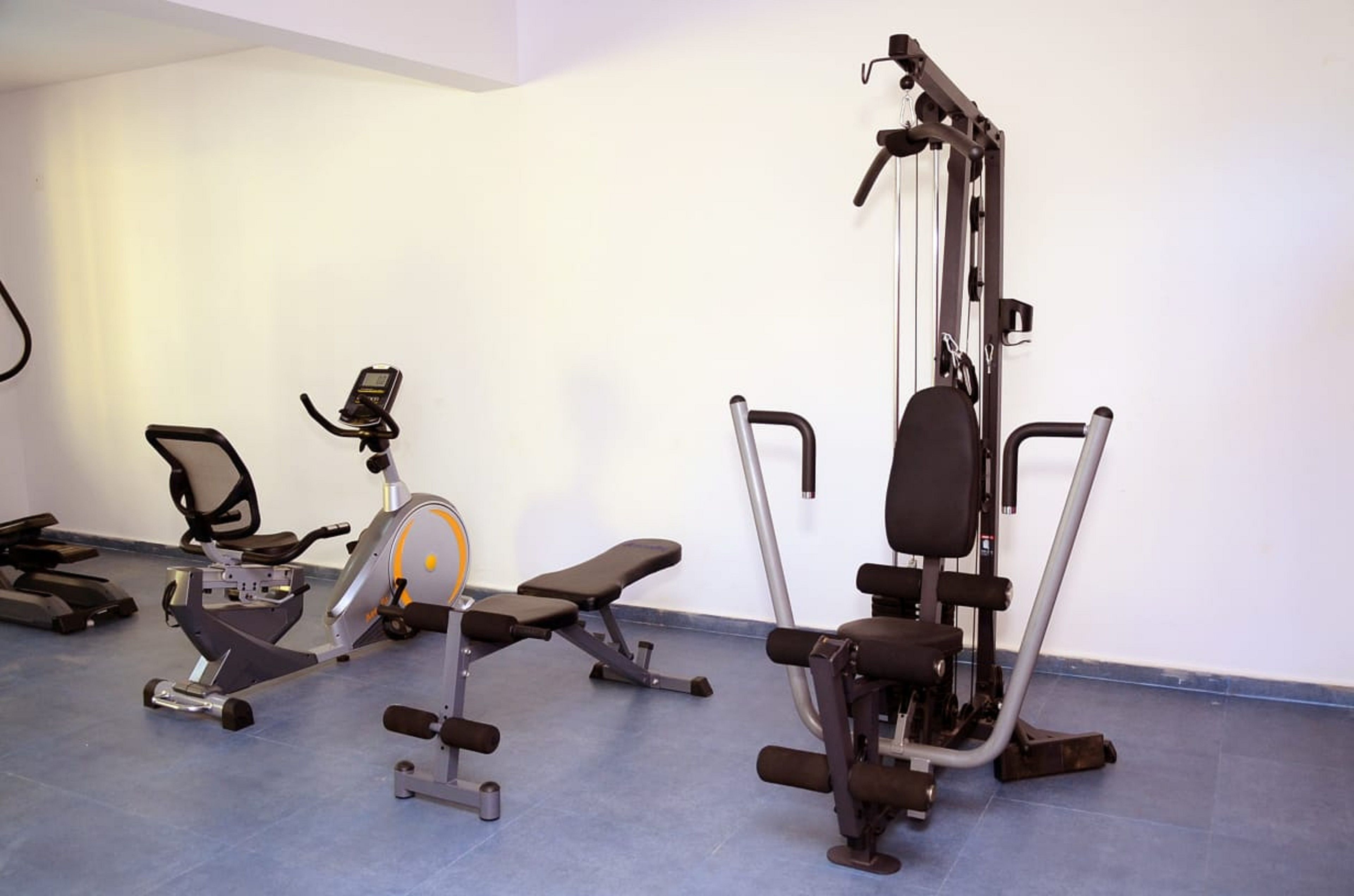 A gym with various exercise equipment including an elliptical, a bench, and a weight machine.
