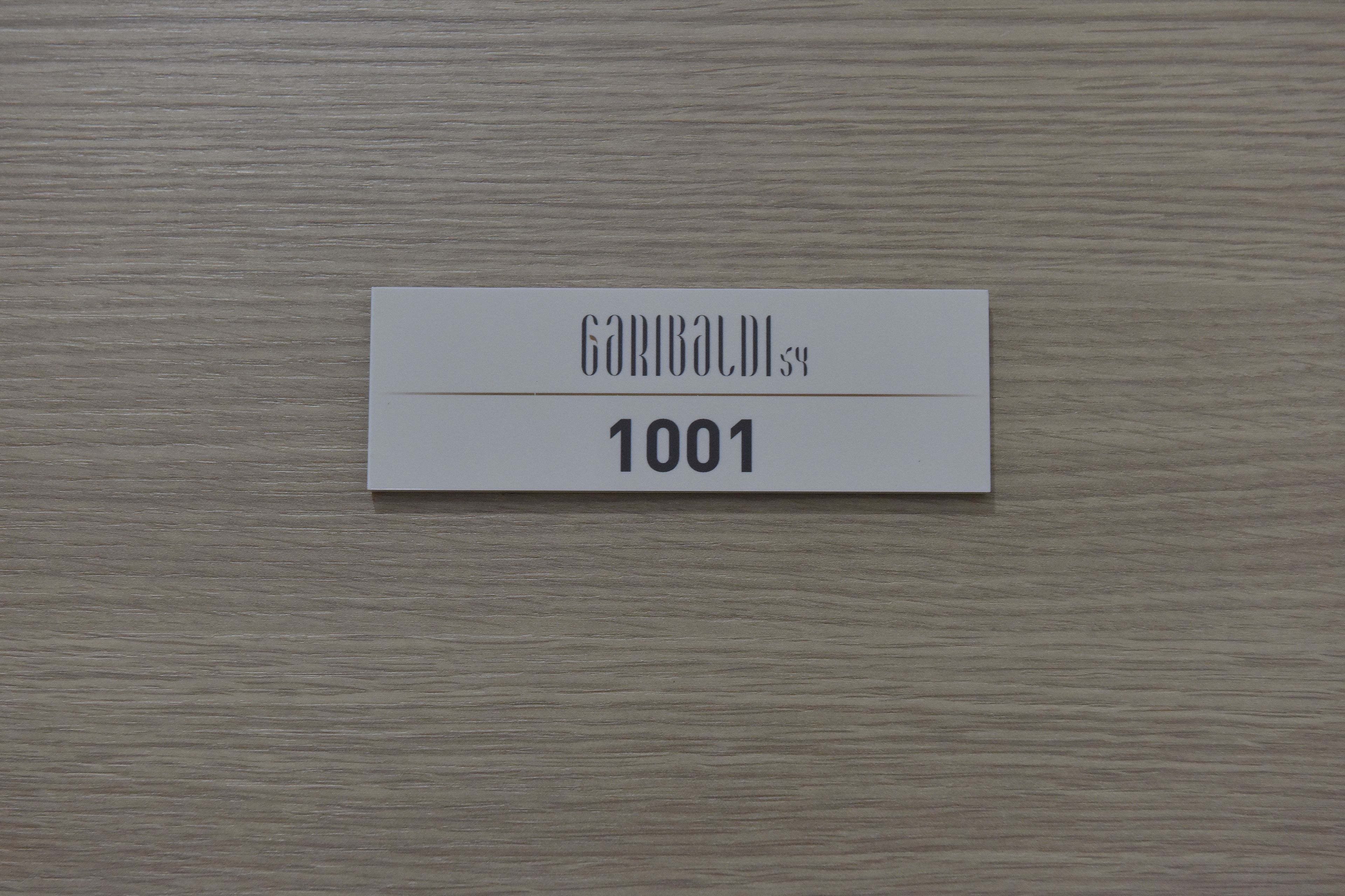 A white sign with the text "GARIBALDI 54" and the number "1001" on a wooden background.